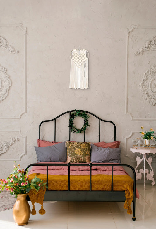 Tenture macramé Amour accrochée au-dessus de la tête du lit d'une chambre colorée et féminine