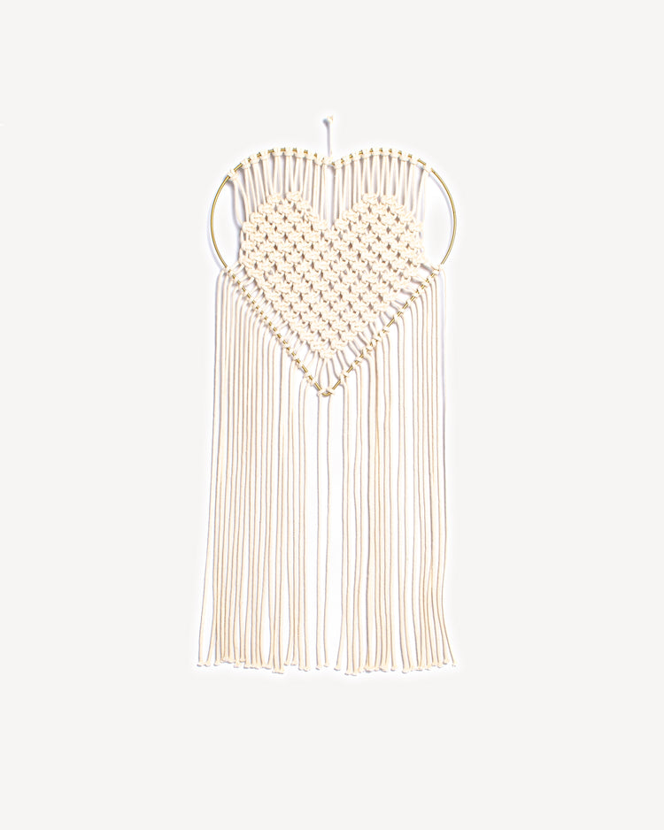 Macramé mural en forme de cœur avec tissage écru et support doré.
