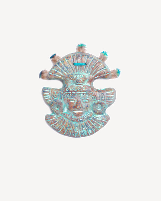 Masque mural en terre cuite bleue avec plumes de paon, création artisanale inspirée du Mexique.
