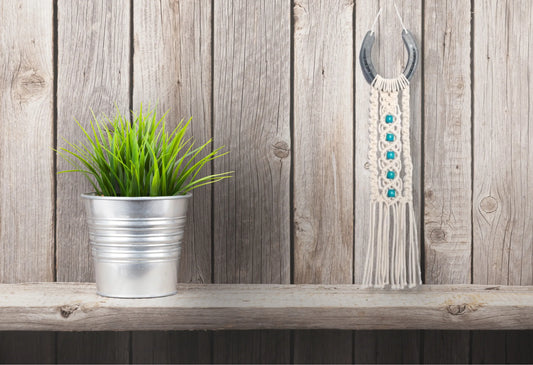 Décoration macramé et fer-à-cheval accrochée sur un mur en planches de bois