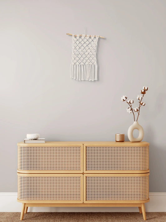 Tenture en macramé Fleur de vie accrochée au mur au-dessus d'un meuble en bois