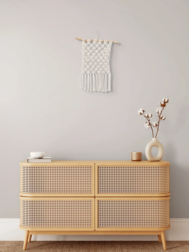 Tenture en macramé Fleur de vie accrochée au mur au-dessus d'un meuble en bois