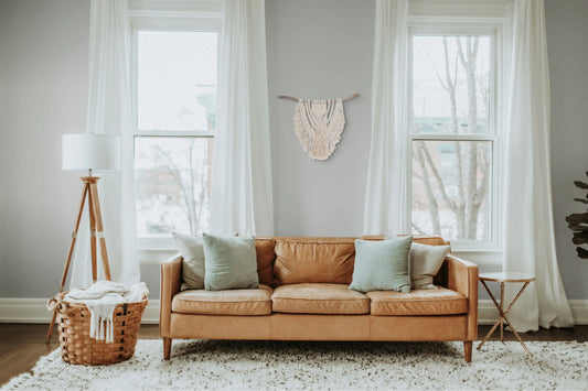 Jolie tenture macramé murale suspendue au mur d'un salon derrière un canapé.