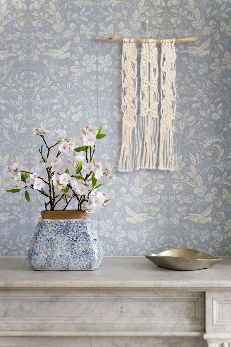 Tenture macramé Arbre à papillons accrochée sur un mur avec une tapisserie vintage