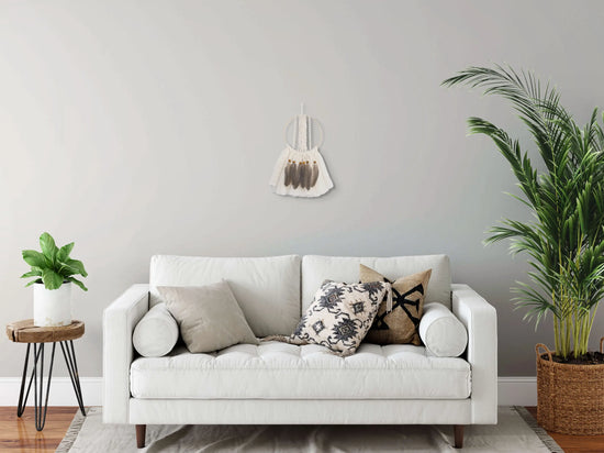 Attrape-rêves suspendu au mur derrière un canapé blanc en tissu