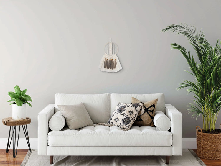 Attrape-rêves suspendu au mur derrière un canapé blanc en tissu