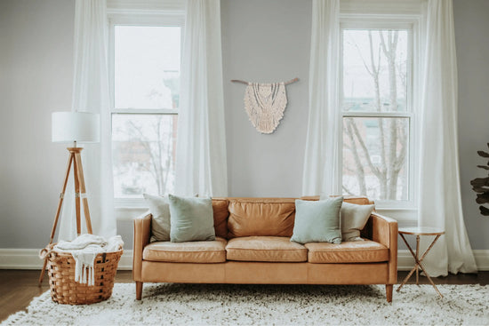 Grande tenture en macramé accrochée au mur d'un salon entre deux fenêtres