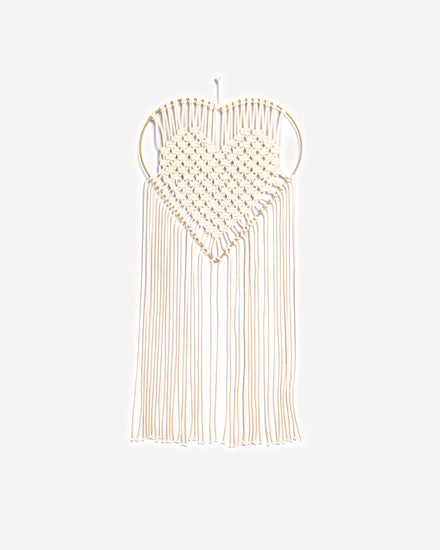 Macramé mural en forme de cœur avec tissage écru et support doré.