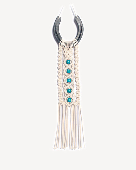 Porte-bonheur mural en macramé avec fer à cheval et perles turquoise.