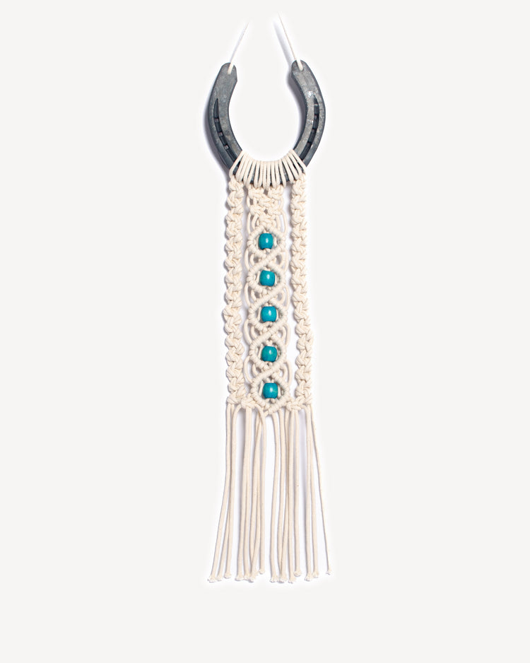 Porte-bonheur mural en macramé avec fer à cheval et perles turquoise.