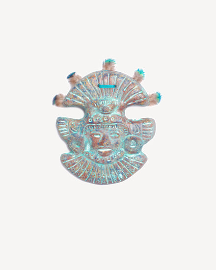 Masque mural en terre cuite bleue avec plumes de paon, création artisanale inspirée du Mexique.