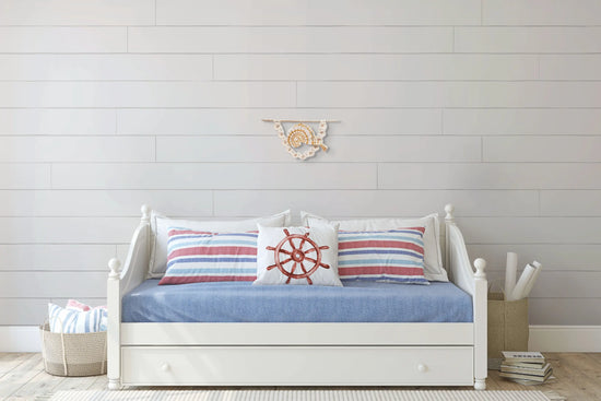 Tenture macramé Nautile pendue au-dessus d'un sofa dans un salon de style marin.