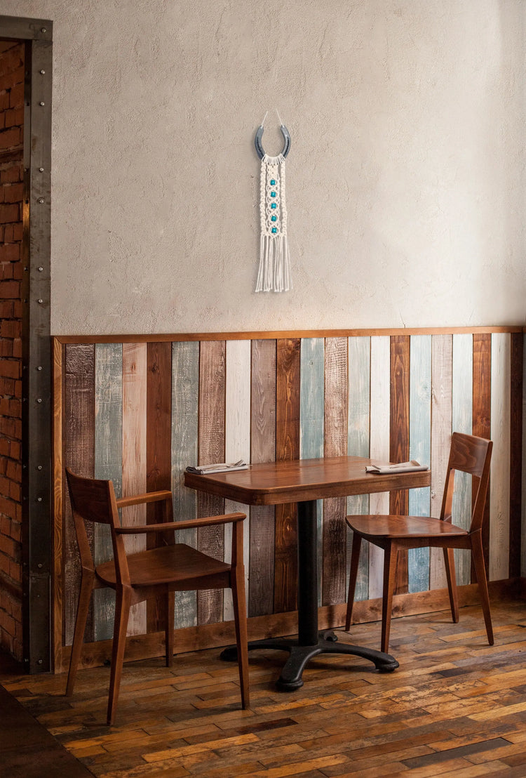 Décoration macramé et fer-à-cheval suspendue au-dessus d'une petite table en bois