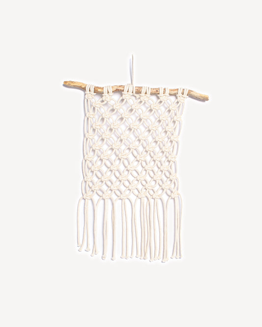 Tenture murale fleur de vie en macramé écru suspendue à une branche de bois naturel, création artisanale faite main.